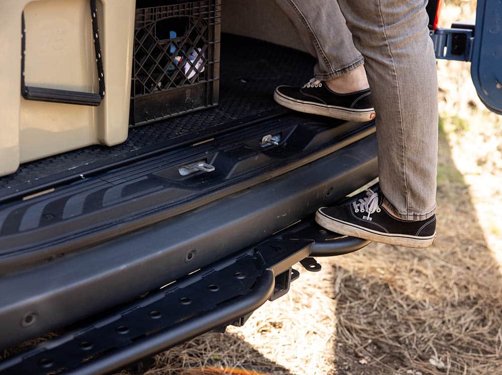 Person using rear tube step to access van garage