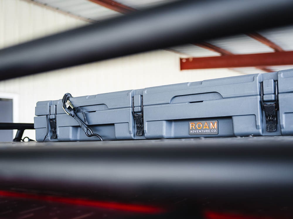 Roam Adventure 83L Rugged Case secured to camper van Safari roof rack by cam straps with S-hooks