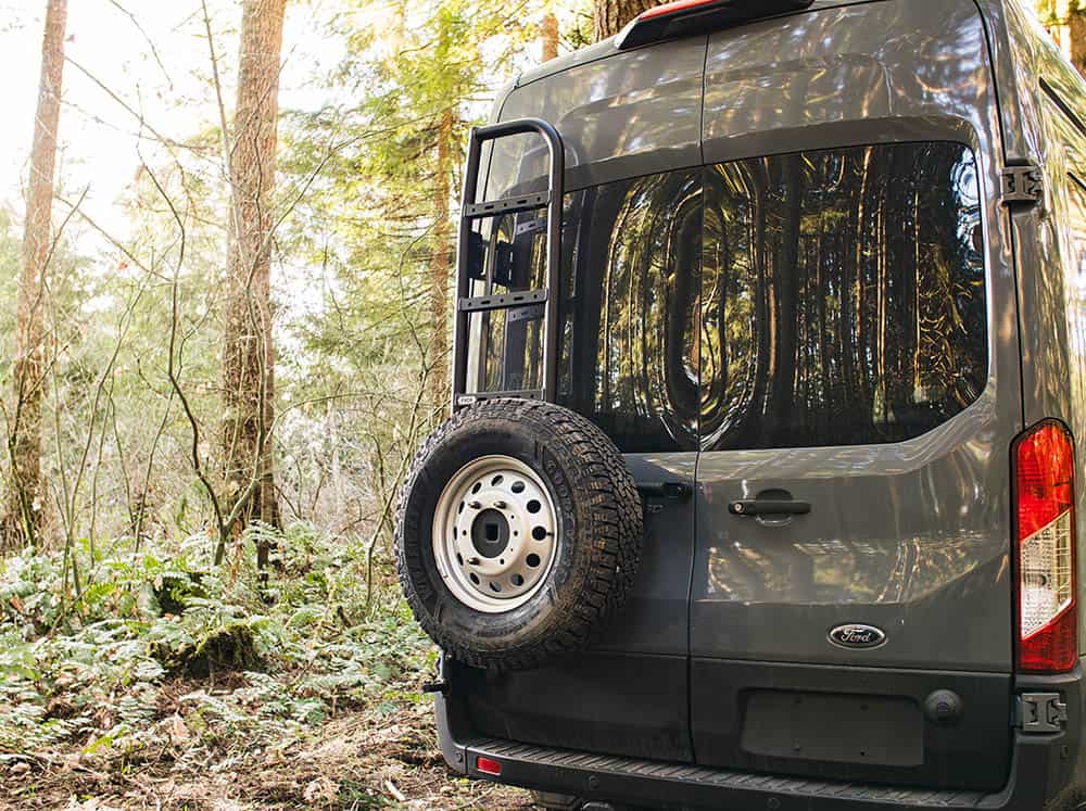Transit van rear tire carrier and ladder on van in the woods