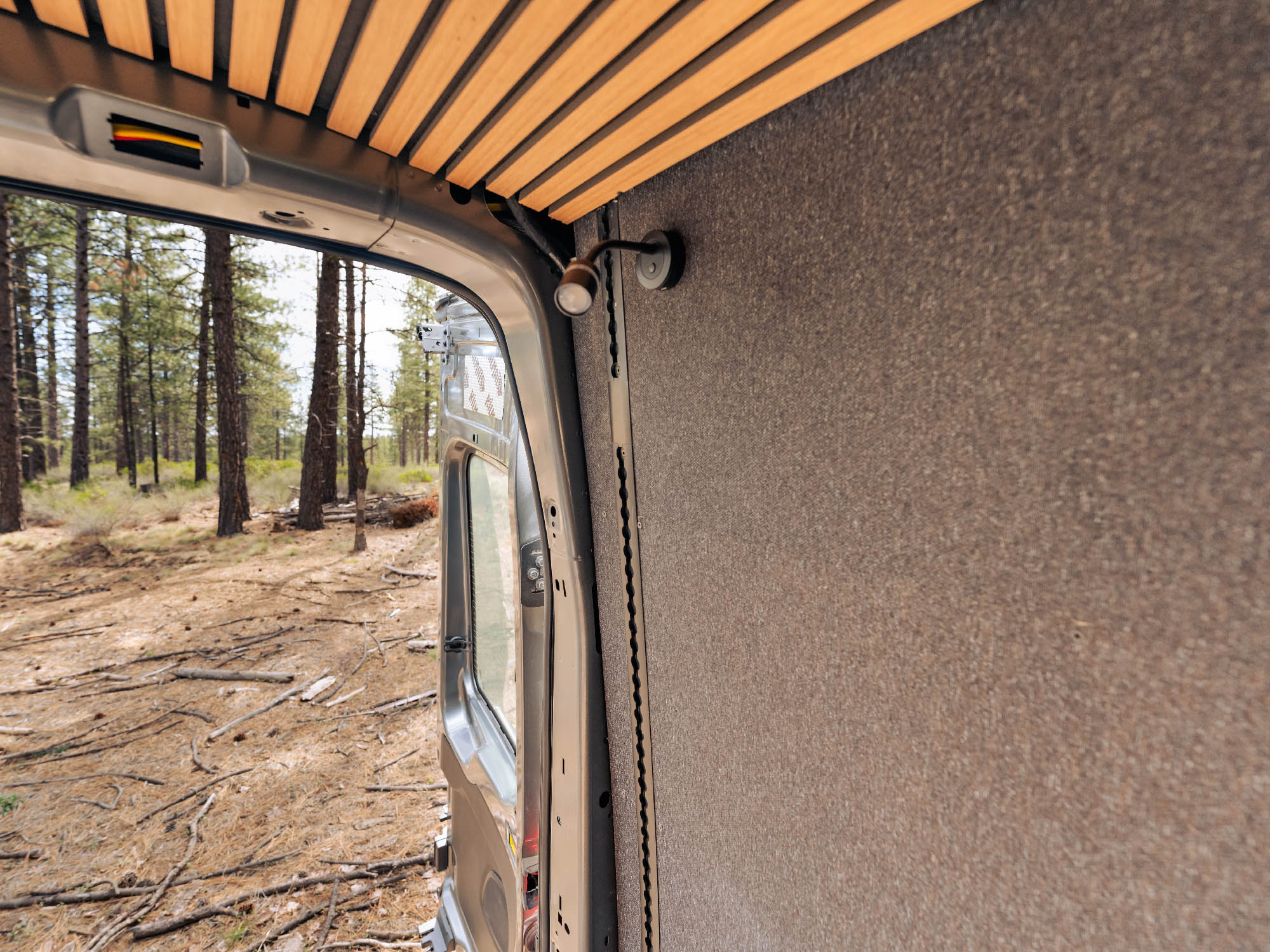 Looking out the rear doors of Ford Transit van with Transit Bed Bracket Flush Mount L-Track, showing it installed all the way to the ceiling