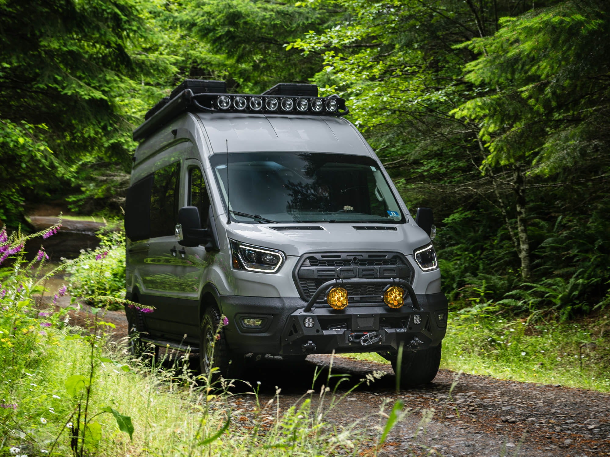 Ford Transit Van driving in the woods with Transit Van Safari Roof Rack installed with gear boxes