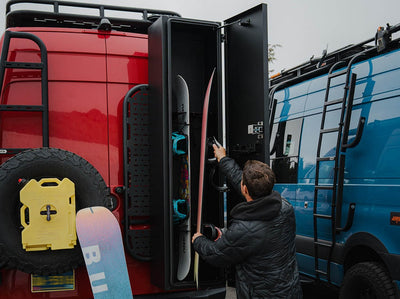 Person loading snowboards in Adventure Van Ski & Snowboard Locker