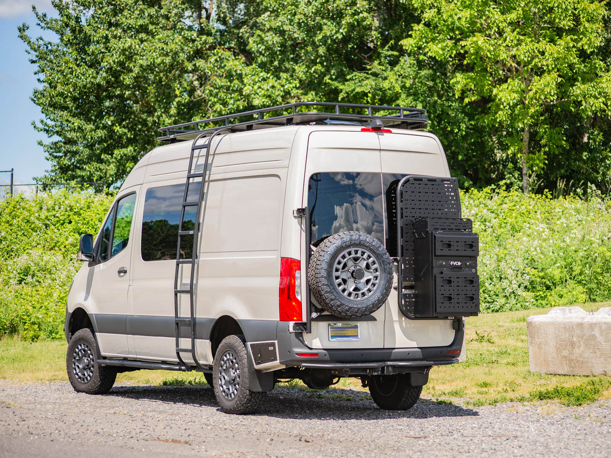 Sprinter camper van parked in gravel with Slim Rear Storage Box Topper, Sprinter Rear Door Platform, Tire Carrier, Rocker Lockers, Side Ladder, and Safari Roof Rack from FVC installed on the van
