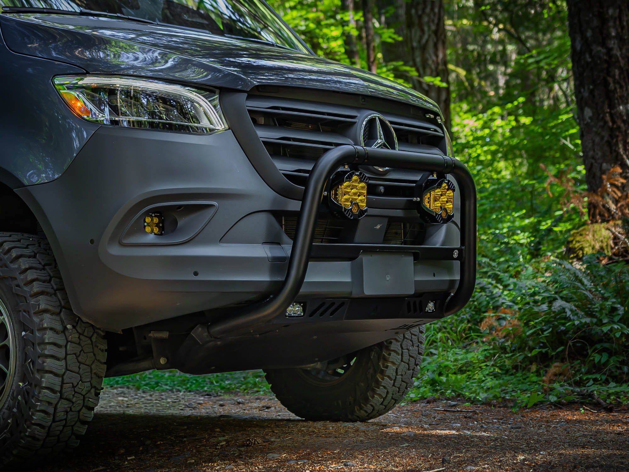 Sprinter Bull Bar installed on van with auxiliary round lights and pod lights while driving in the woods