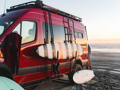 Camper van on the beach with surfboards and surf pole installed